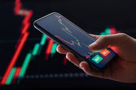 Hand holding a smartphone displaying a stock trading app with buy and sell buttons.